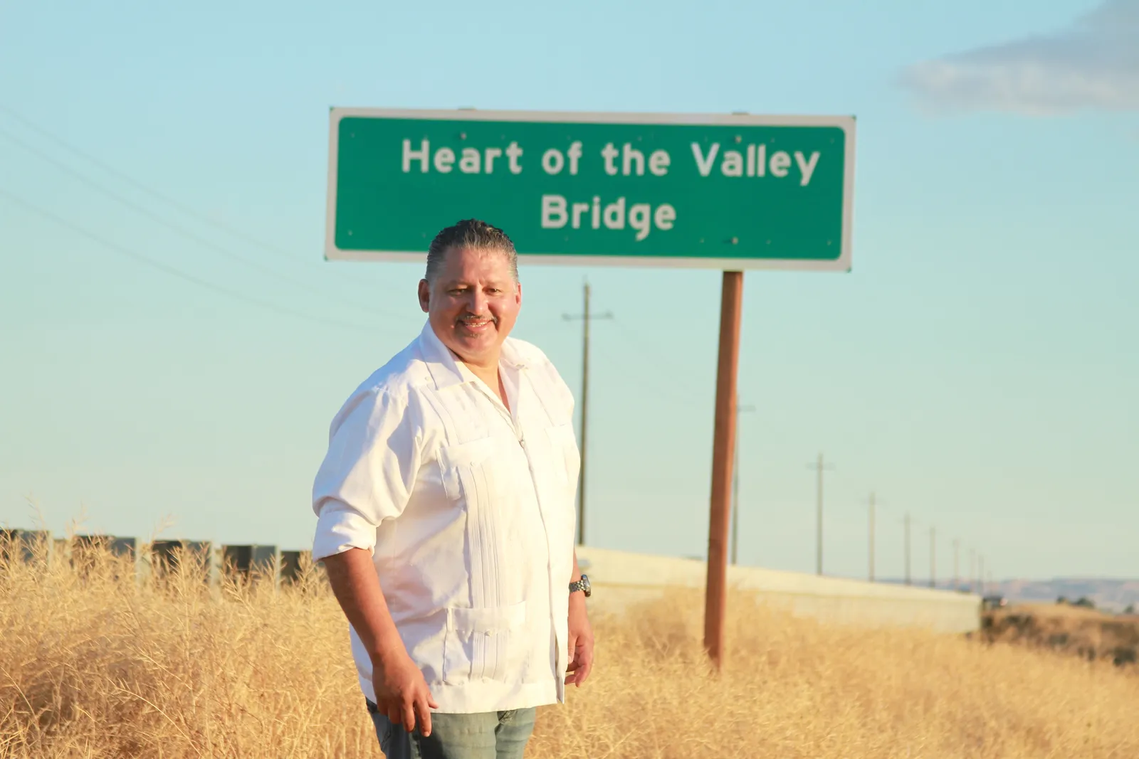 Rey León standing in front of the Heart of the Valley Bridge sign